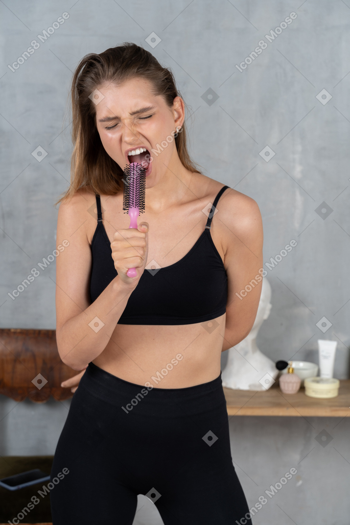 Young woman hitting high notes with "mic" in hand