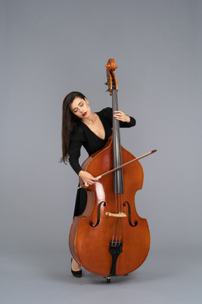 Front view of a young woman in black dress playing the double-bass with a bow