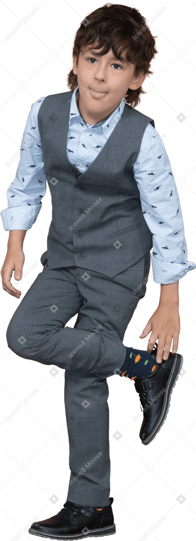 Vista frontal de um menino de terno cinza em pé em uma perna