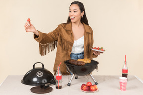 Giovane donna asiatica facendo un barbecue e tenendo il piatto di fragole