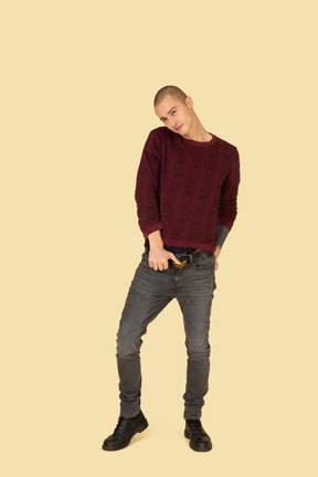 Вид спереди молодого человека в красном пуловере трогательно пояс