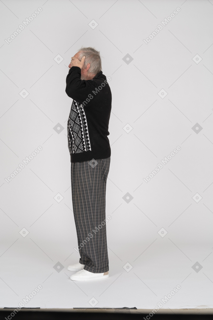 Side view of old man covering eyes