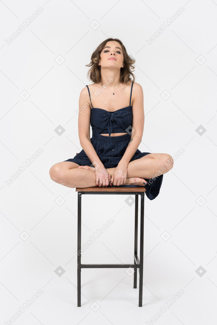Mujer joven sentada en posición de loto en la silla de la barra