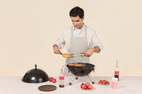 Giovane uomo caucasico cucina barbecue