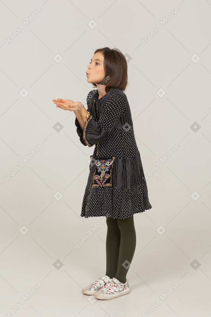 Vista de tres cuartos de una niña vestida enviando un beso al aire