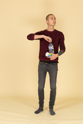 Front view of a young man in red sweater ready to pour some water