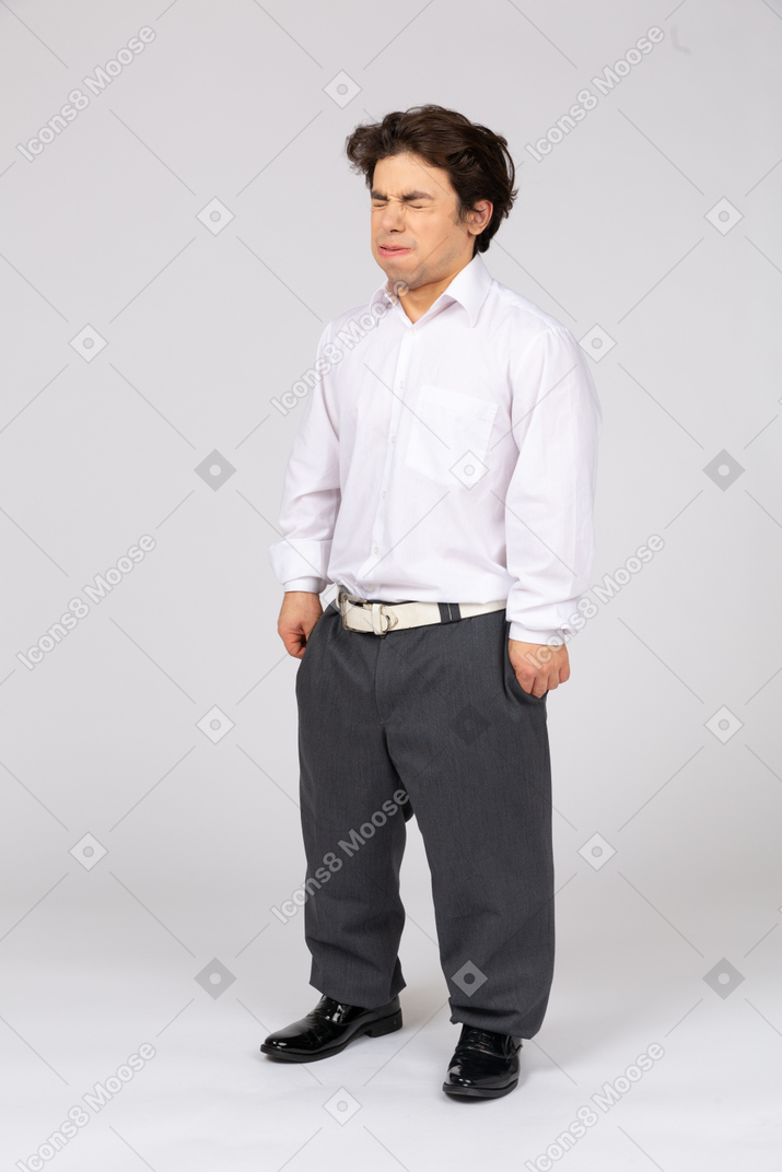 Молодой человек в рубашке и брюках чихает