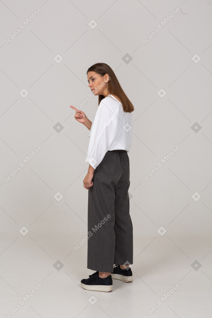 Vista posteriore di tre quarti di una giovane donna attenta in abiti da ufficio che alza il dito