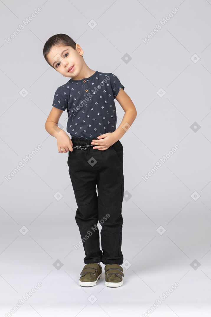 Front view of a cute boy posing with hand on stomach and looking at camera