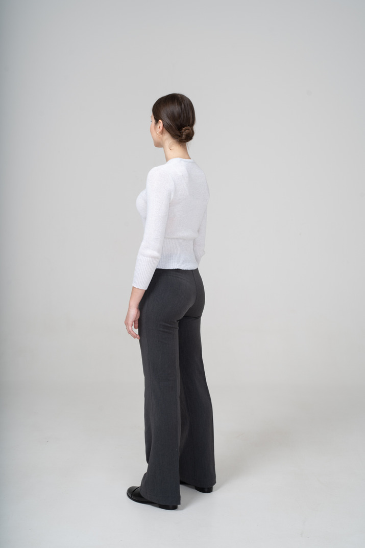 Young woman in white blouse and black pants posing in profile
