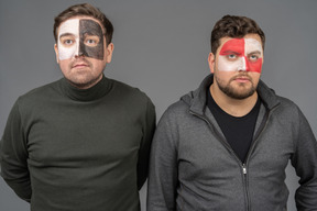 Front view of two male football fans with face art