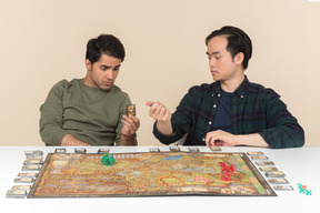 Interracial friends sitting at the table and playing board game