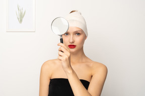 拡大鏡を保持している包帯の頭を持つ若い女性