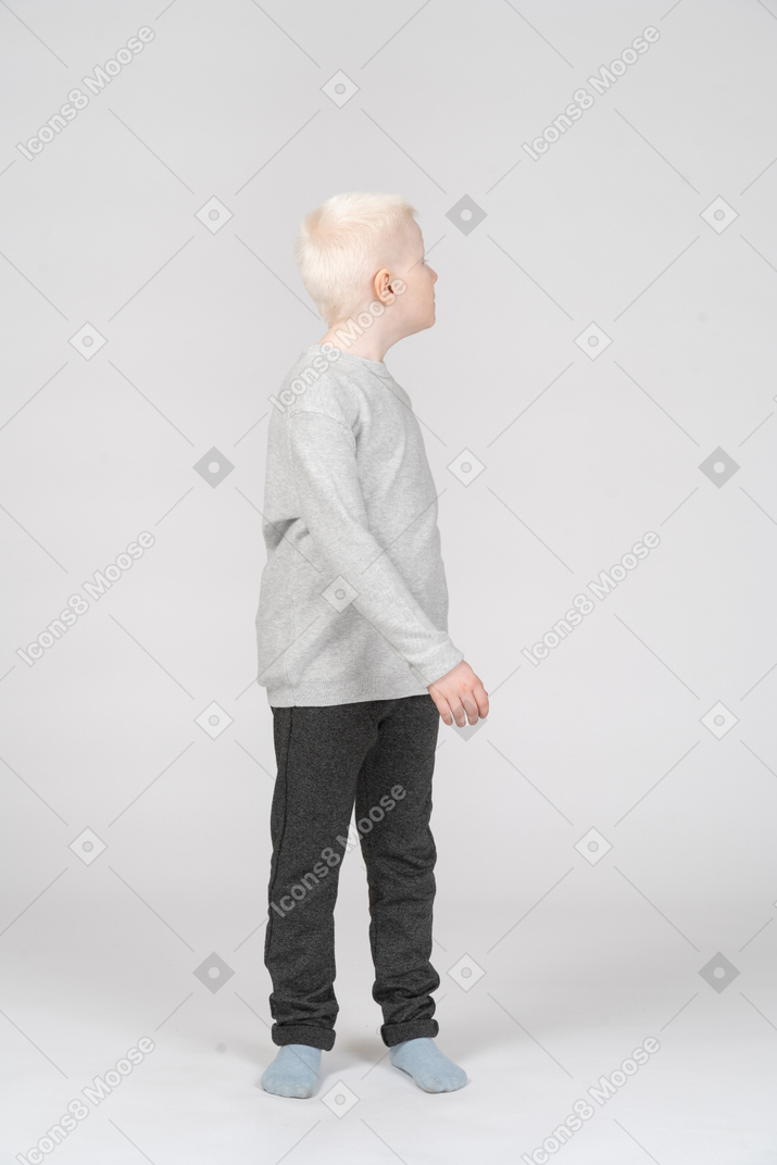 Front view of a walking little blond boy looking sideways