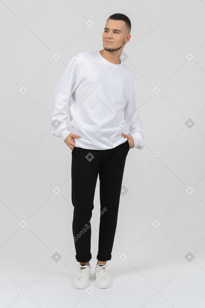 Smirking young man standing with his hands in his pockets