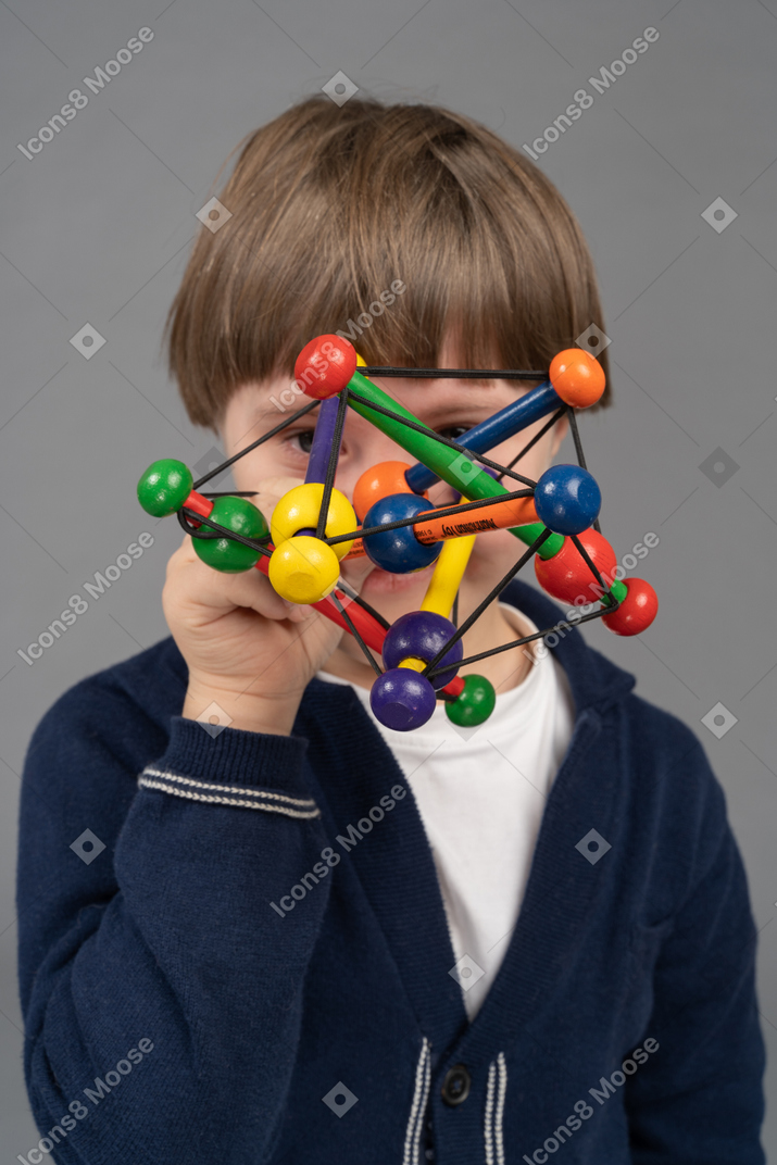 Little boy looking at camera through colorful toy