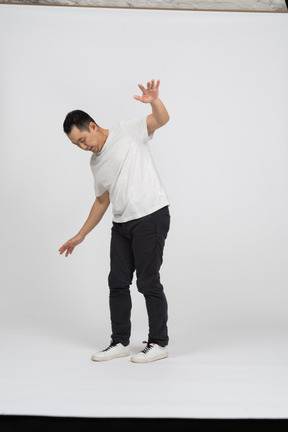 Vista lateral de un hombre con ropa informal caminando con los brazos extendidos