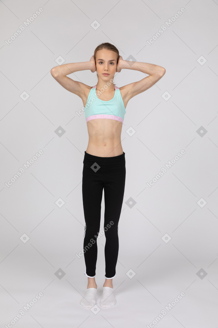 Una adolescente con ropa deportiva cubriendo los oídos con las manos.
