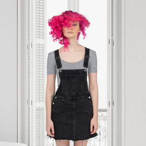 A woman with pink hair standing in a room