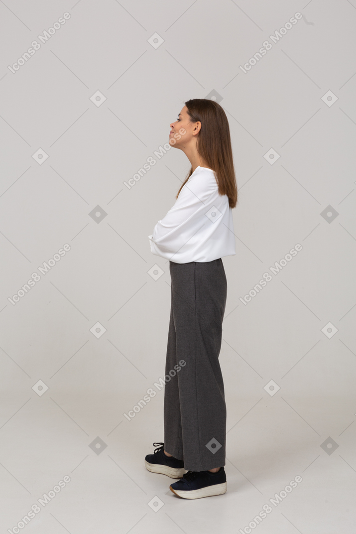 Vista laterale di una giovane donna sospettosa in abiti da ufficio che guarda da parte