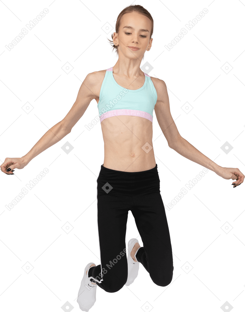 Vista frontal de uma adolescente em roupas esportivas pulando e dobrando os joelhos