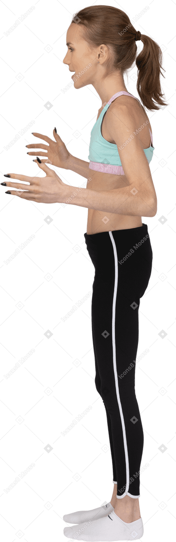 Vista laterale posteriore di una ragazza adolescente in abiti sportivi alzando le mani e litigando