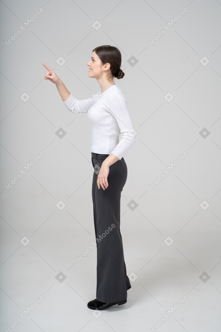 一个穿着黑色裤子和白色衬衫的年轻女子用手指指着的侧视图