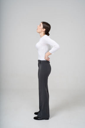 Vista lateral de uma jovem mulher com roupas casuais, posando com as mãos na cintura