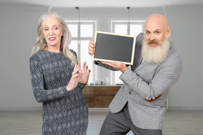 A man with a beard and a woman holding a blackboard