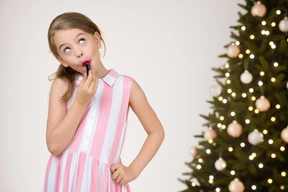Young girl putting lipstick on her lips before christmas party