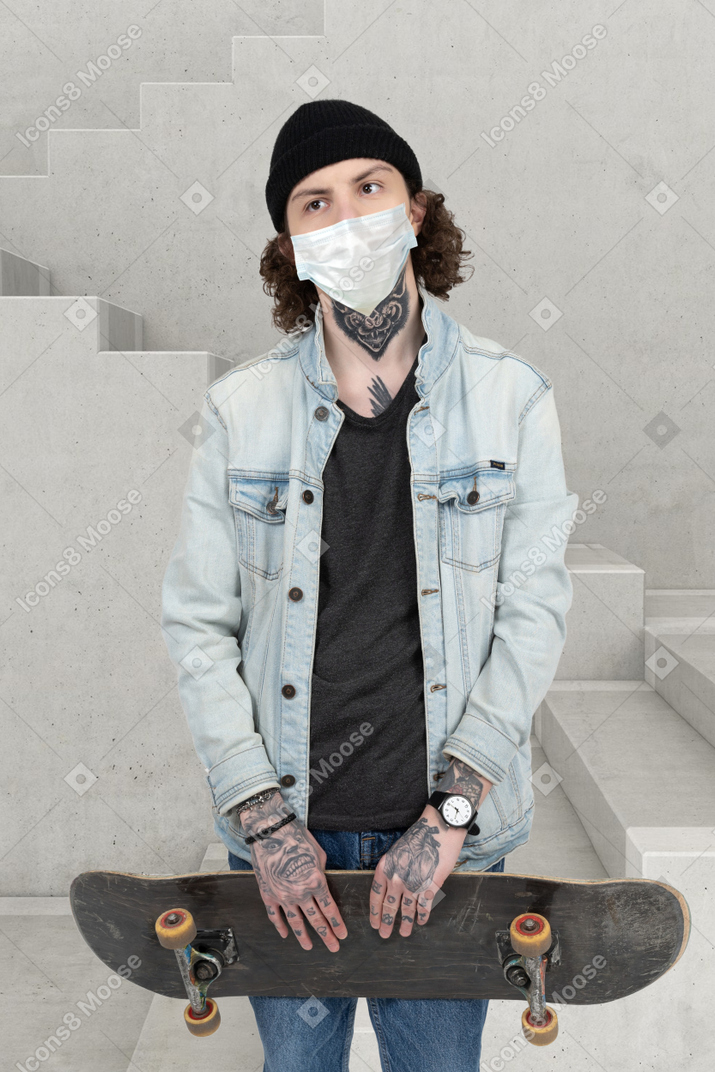 A man with a face mask holding a skateboard