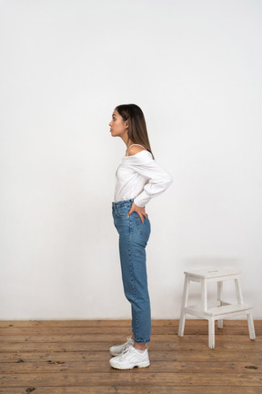 Profile of young woman standing with hands on lower back