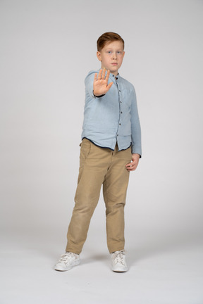 Front view of a boy standing with extended arm and looking at camera
