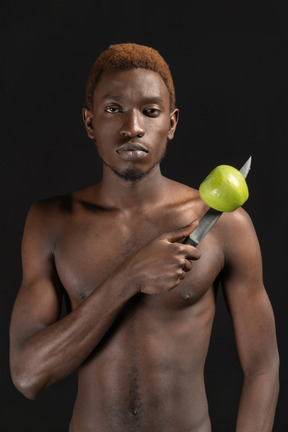 Gros plan un jeune homme sérieux tenant un couteau avec une pomme dessus