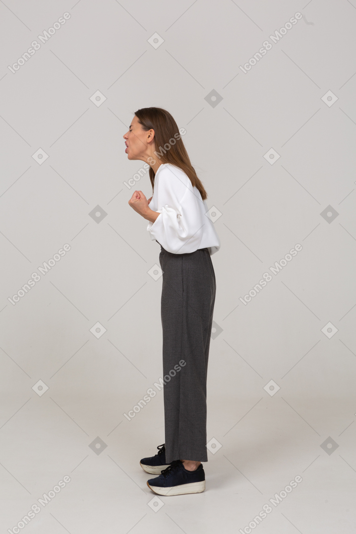 Side view of a swearing young lady in office clothing clenching fists