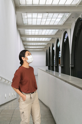 A young woman in a medical mask looking up