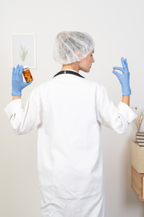 Back view of a young female doctor checking pills