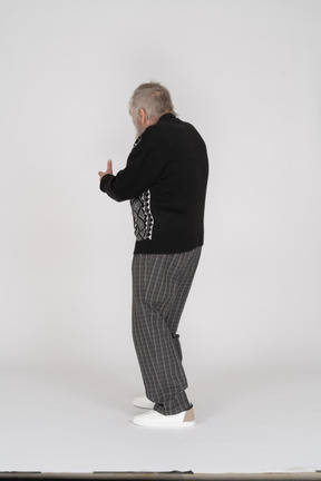 Rear view of an elderly man pointing away