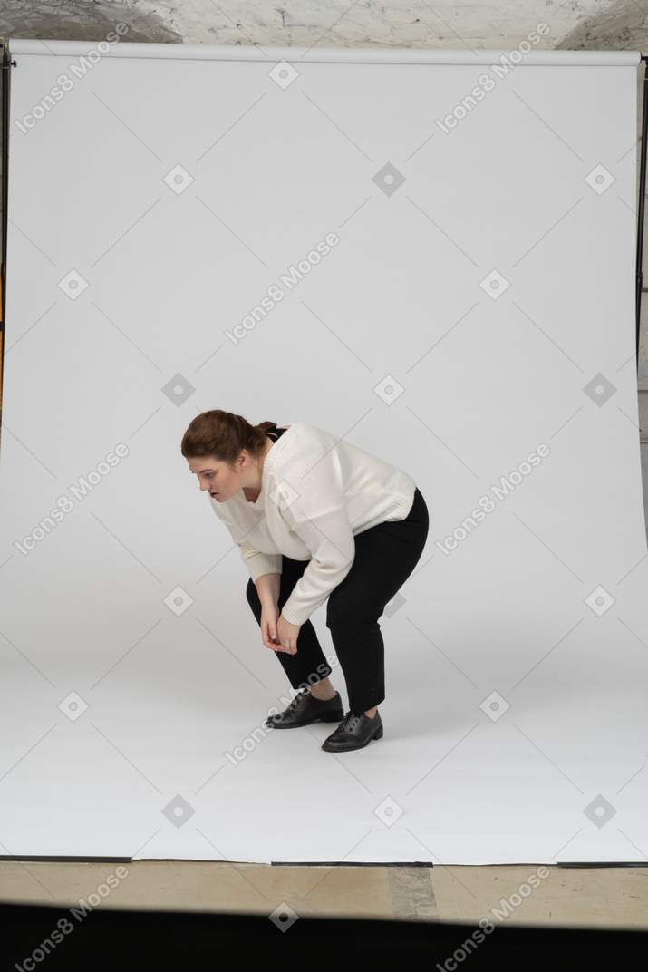 Vista lateral de una mujer regordeta en ropa casual en cuclillas