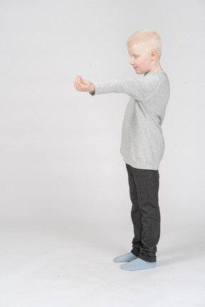 Side view of a boy holding out empty hand