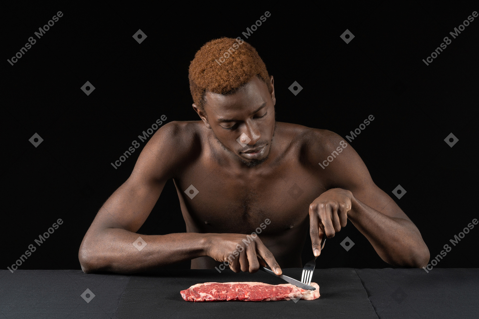 Vista frontal de un joven afro cortando carne