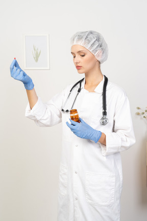 Vista de três quartos de uma jovem médica oferecendo um comprimido