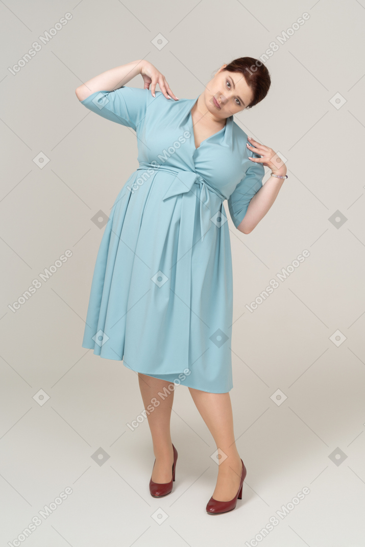 Front view of a woman in blue dress posing with hands on shoulders