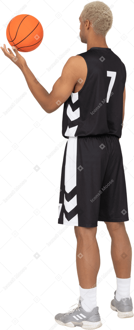 Трехчетвертный вид сзади молодого баскетболиста, держащего мяч