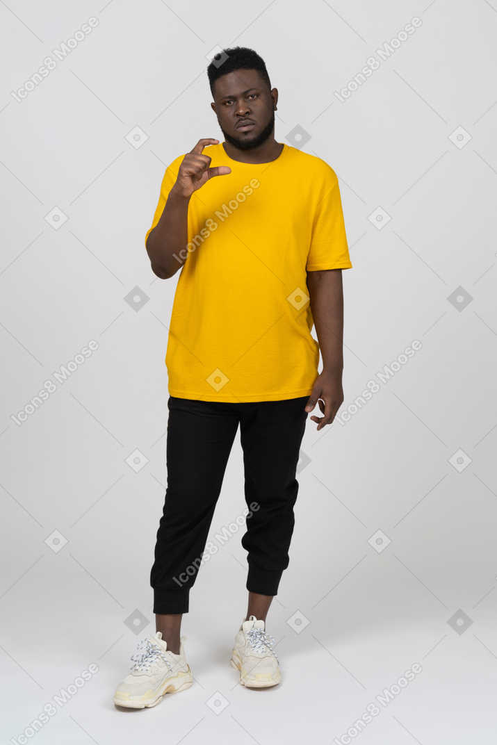 Vista frontal de um jovem de pele escura em uma camiseta amarela mostrando o tamanho de algo