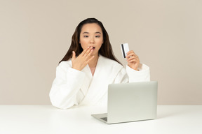 Gasping young asian woman doing online shopping