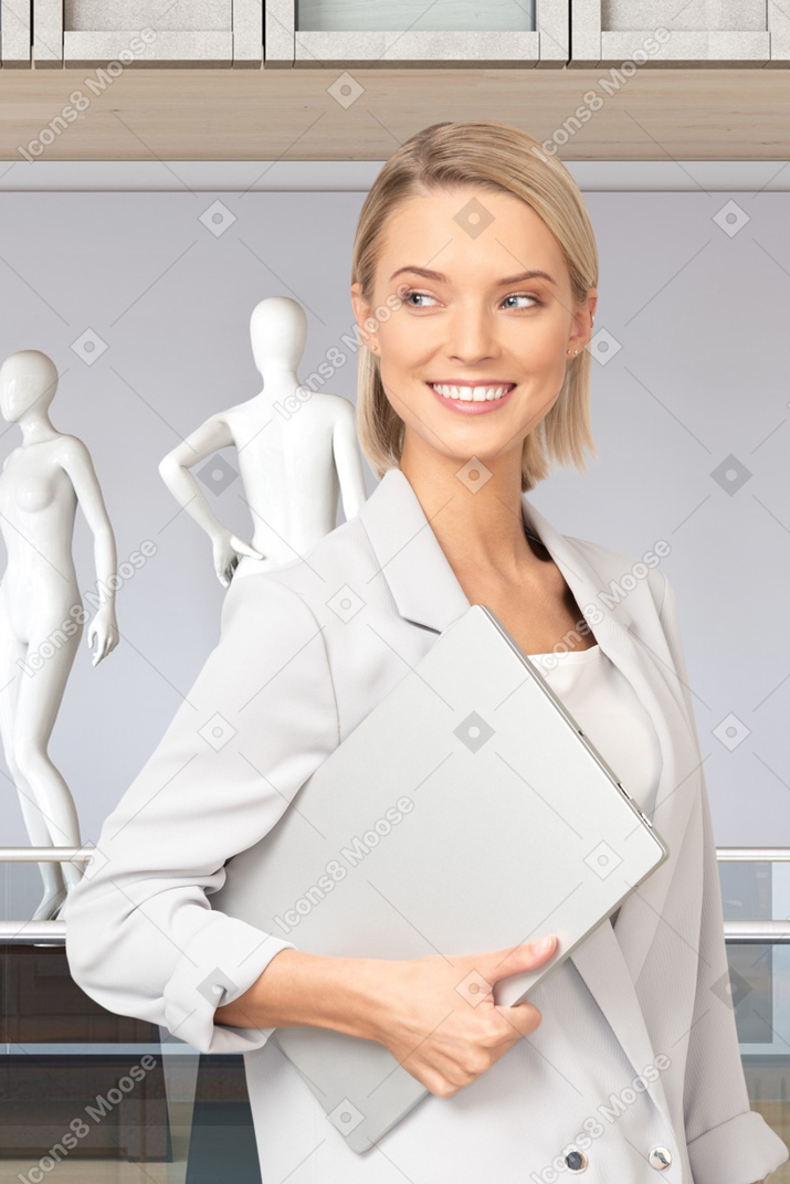 A woman in a white suit holding a laptop