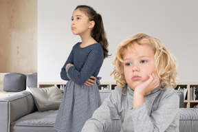 Two children standing in front of a couch in a living room