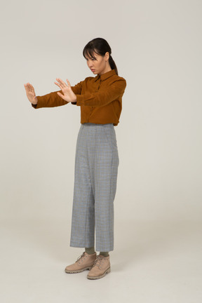 Three-quarter view of a young asian female in breeches and blouse outstretching her arms