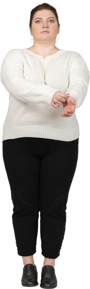 Vista frontal de uma mulher plus size em roupas casuais arregaçando a manga